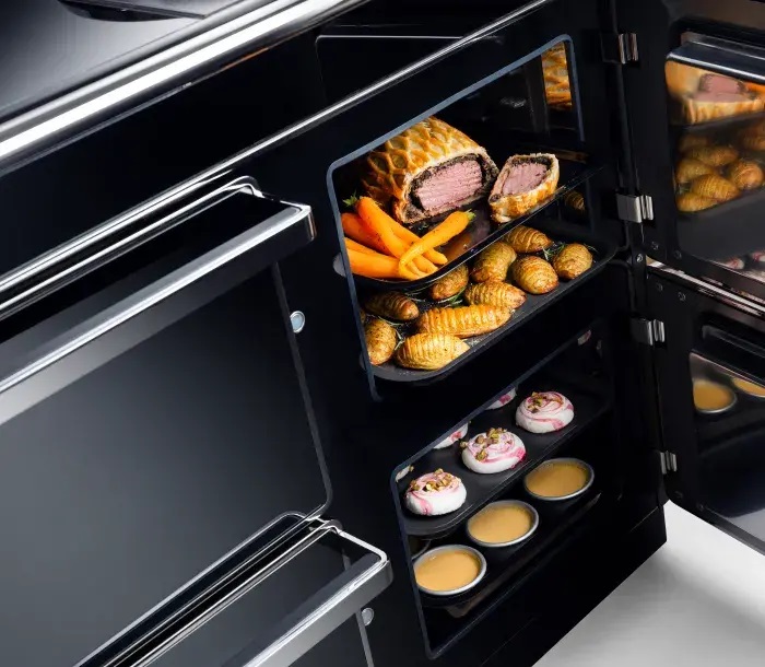 Two ovens with their doors opened. One with a beef wellington and the other with pastries and cakes.