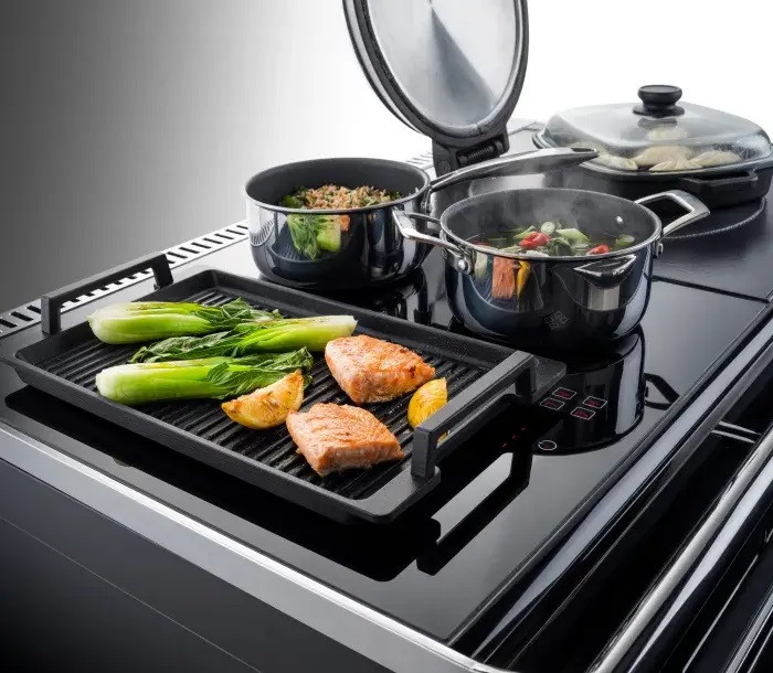 The induction hob with poached salmon on top in a pan.